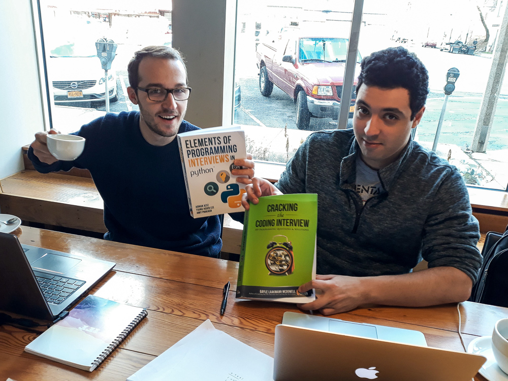two students holding a book in a cafe